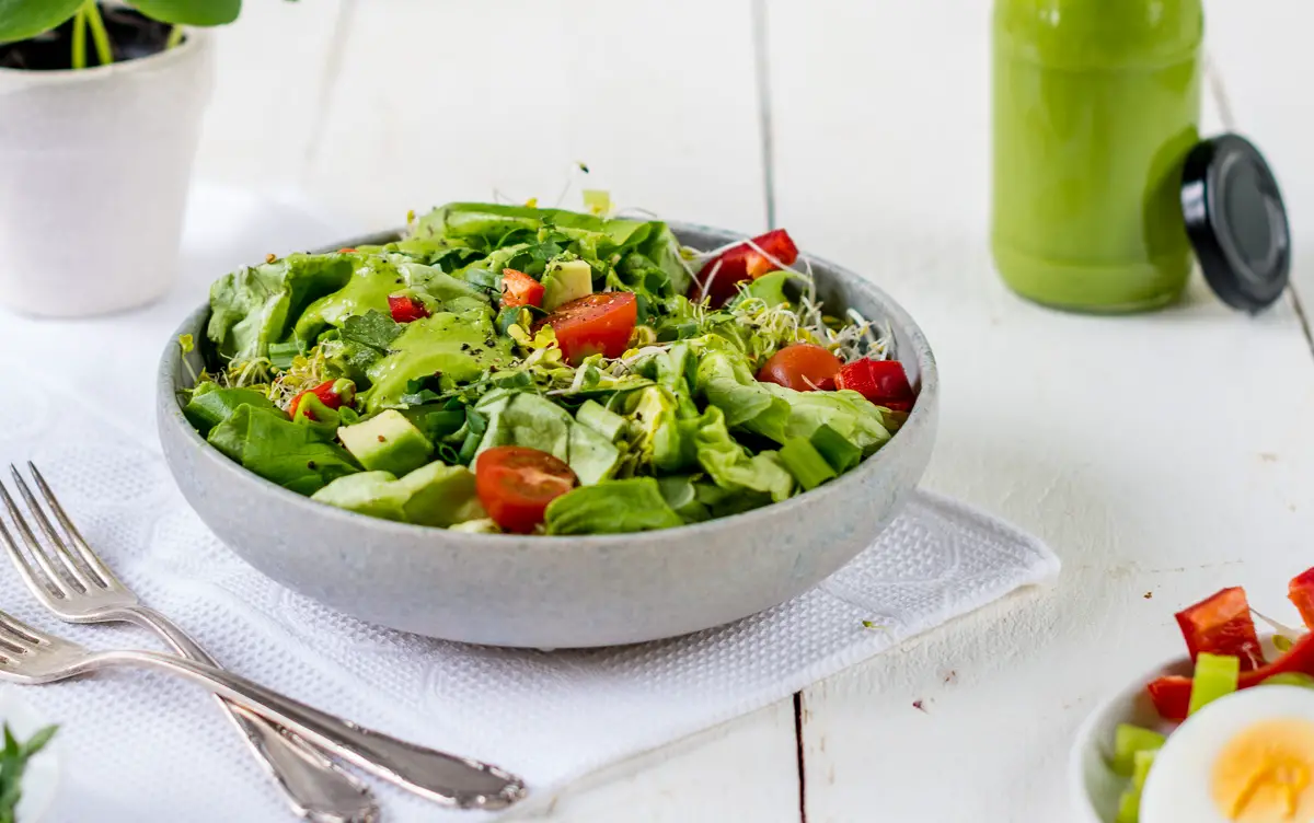 Schüssel mit grünem Salat, Tomaten und Sprossen.