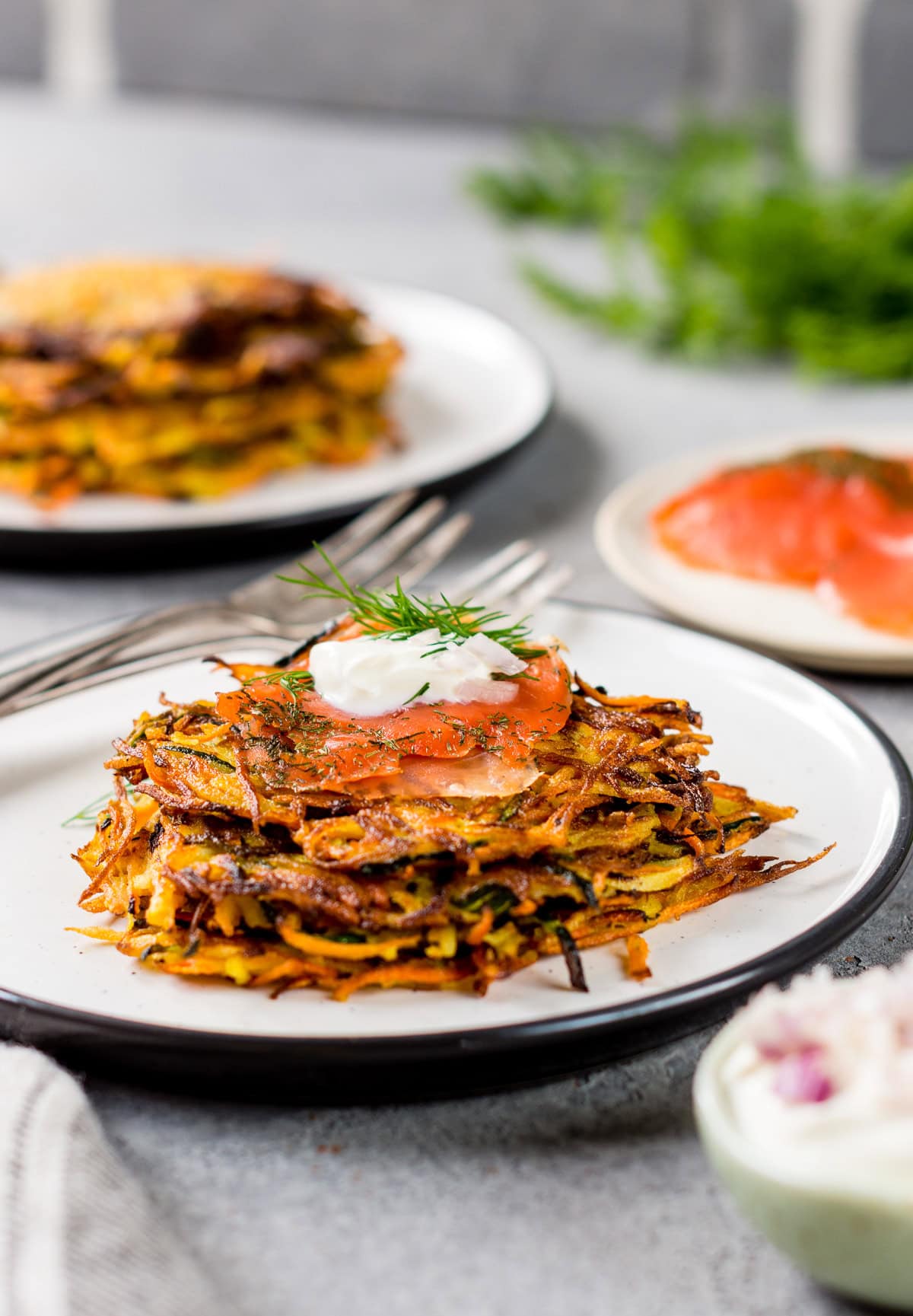 Teller gefüllt mit Zucchini Möhren Puffern und frischem Lachs und Kräuterquark.