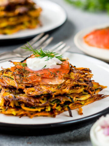 Teller gefüllt mit Zucchini Möhren Puffern und frischem Lachs und Kräuterquark.