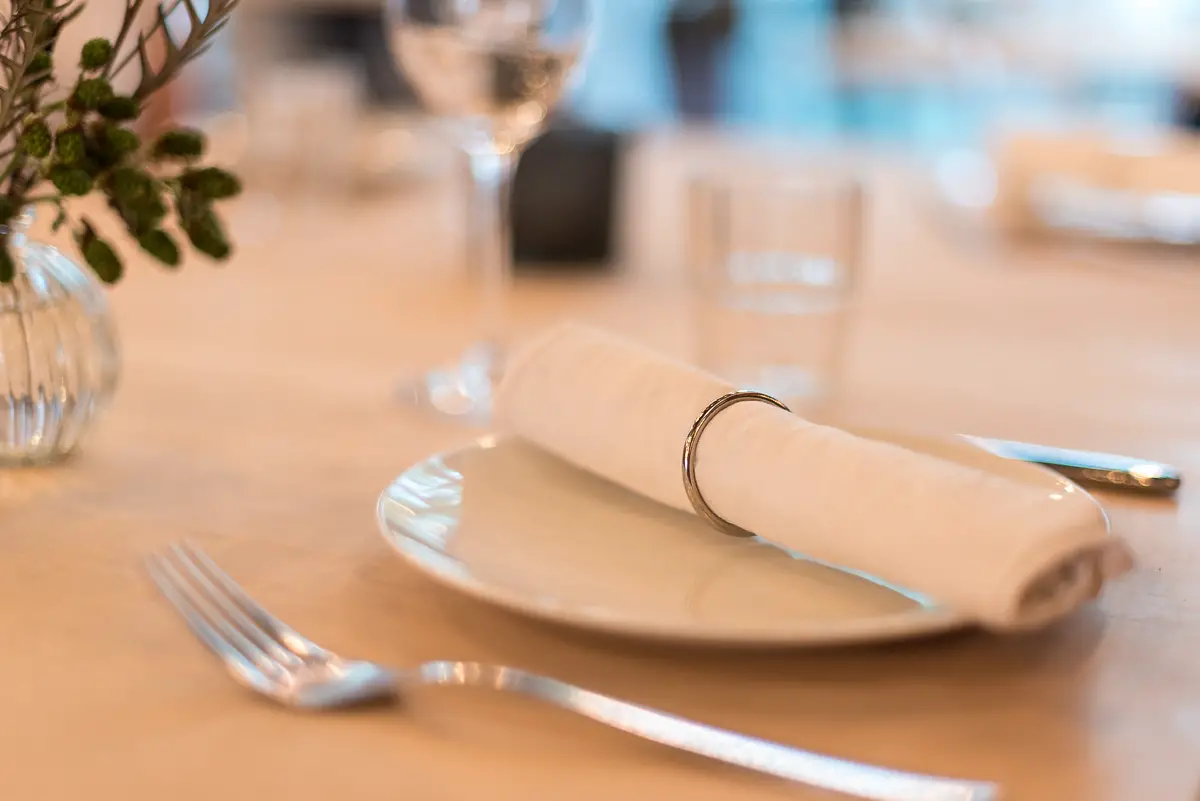 Ein Tisch mit weißem Teller, einer Serviette und Besteck.