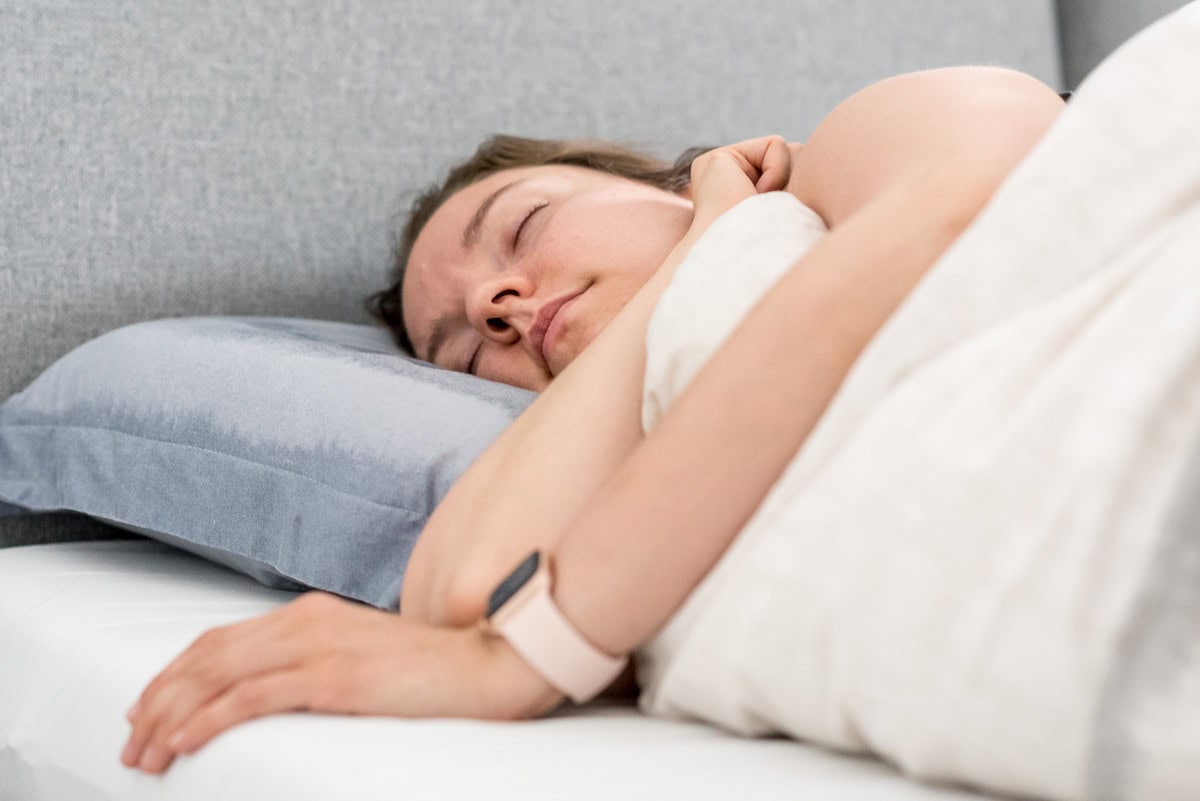 Pinne das Foto, um meine Tipps für eine gesunde Morgenroutine zu speichern! Frau liegt schlafend in einem Bett.