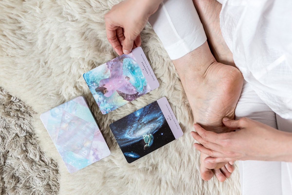 Pinne das Foto, um meine Tipps für eine gesunde Morgenroutine zu speichern! Topshot von Person die im Schneidersitz sitzt und Tarotkarten liest.