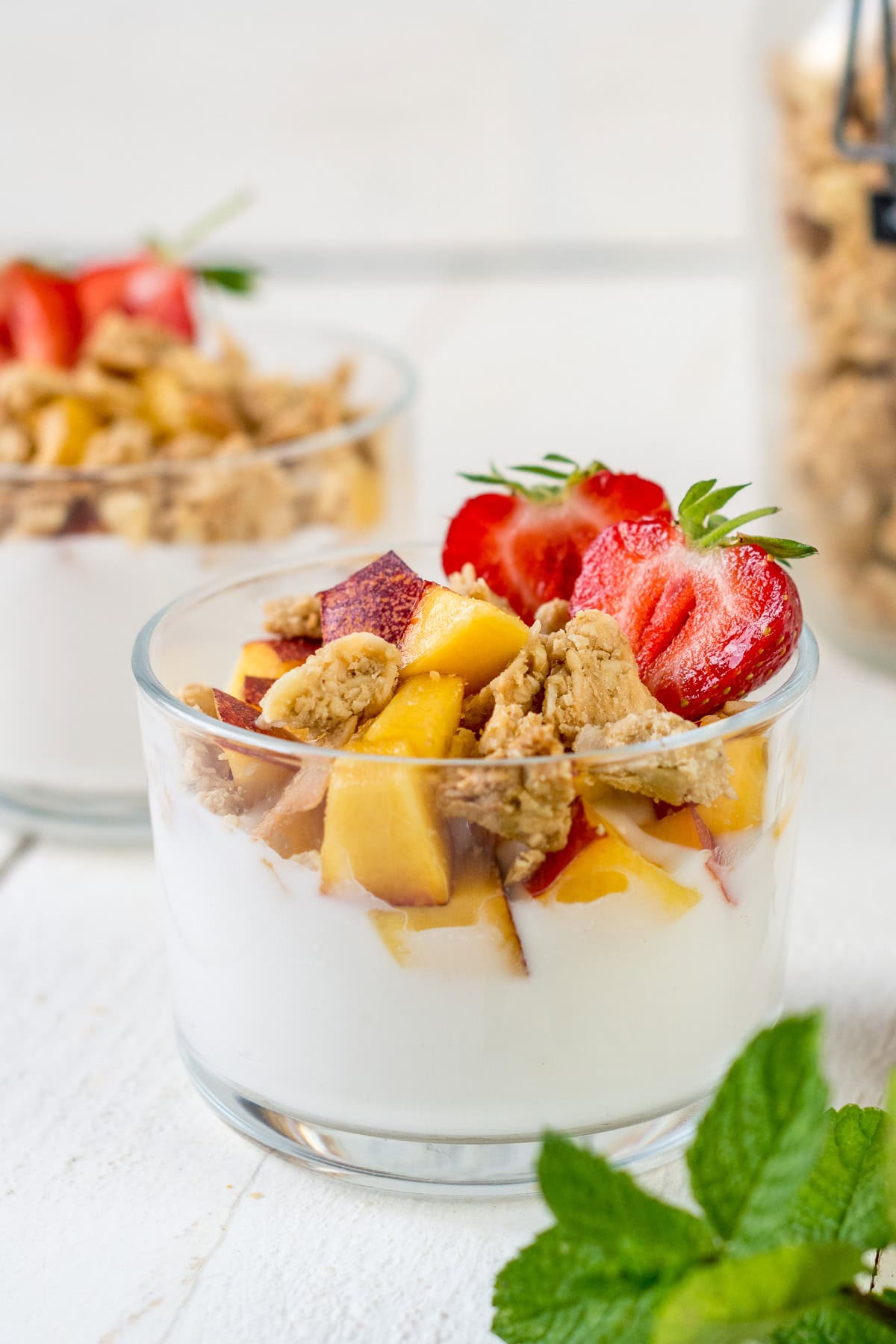 Glas gefüllt mit Joghurt, Früchten und Granola Knuspermüsli.