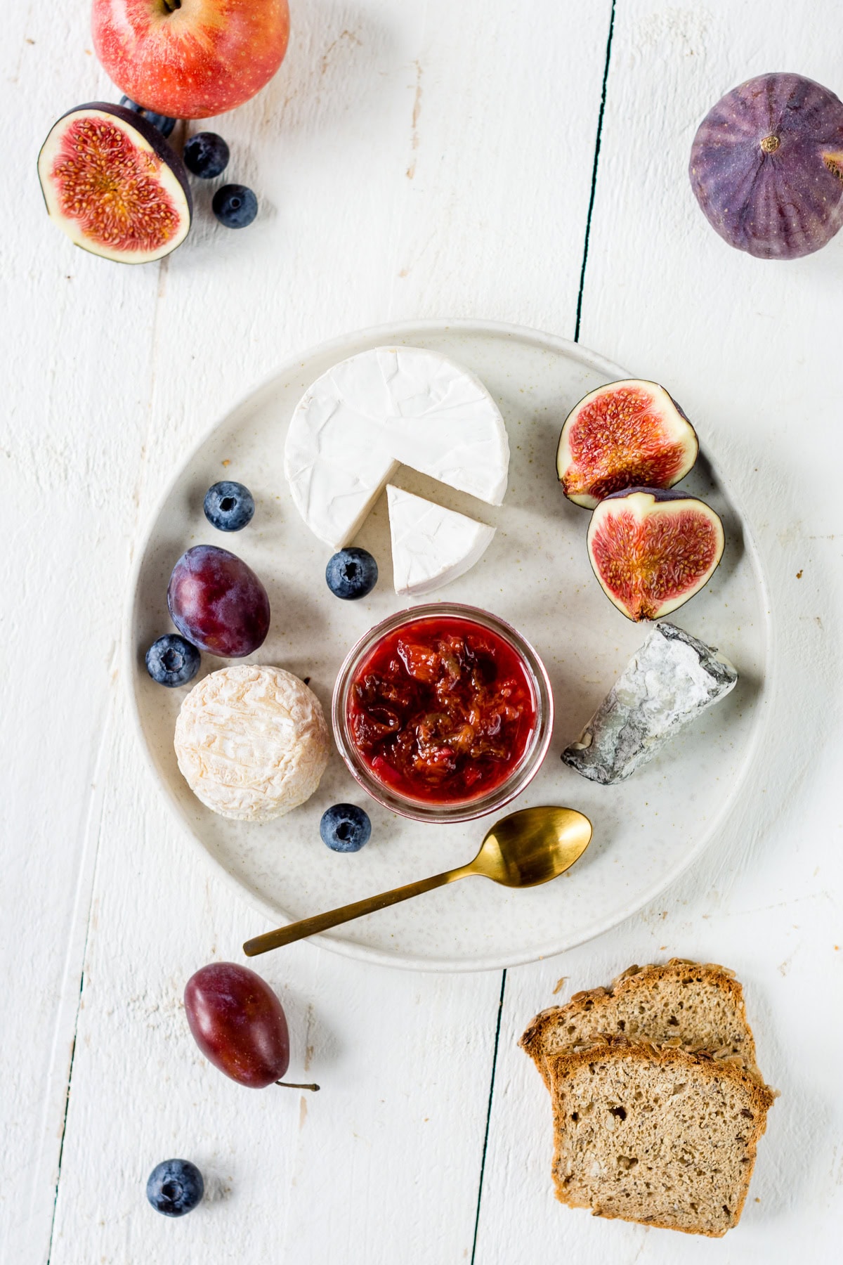 Pinne das Foto, um das vegetarische Weihnachtsmenü zu speichern! Topshot von einem Teller mit Weichkäse, Feigen, Zwetschgen und einem Glas Chutney.
