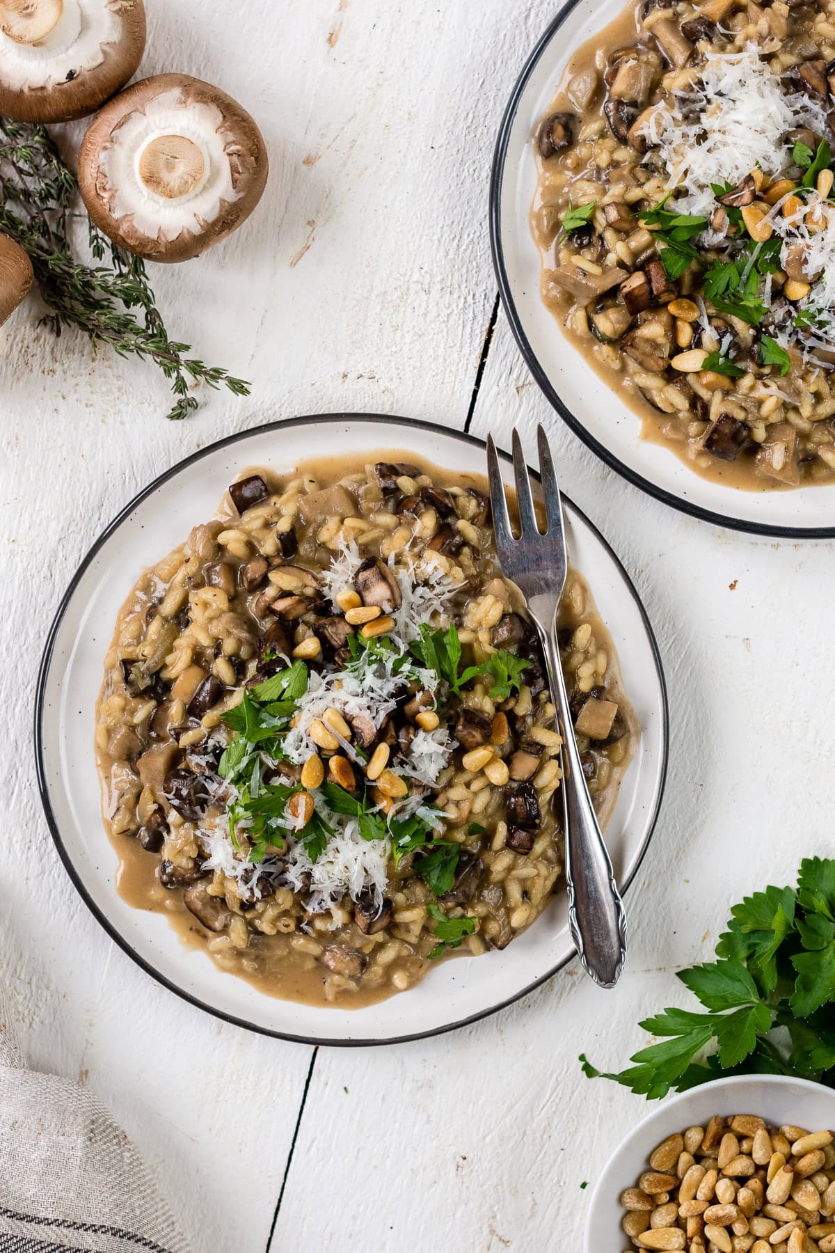 Topshot von einem Teller mit cremigem Pilzrisotto, Kräutern und Parmesan.