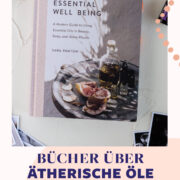 Buch über essential well being, ein ätherisches Öl in einer dunklen Flasche und verschiedene Postkarten.