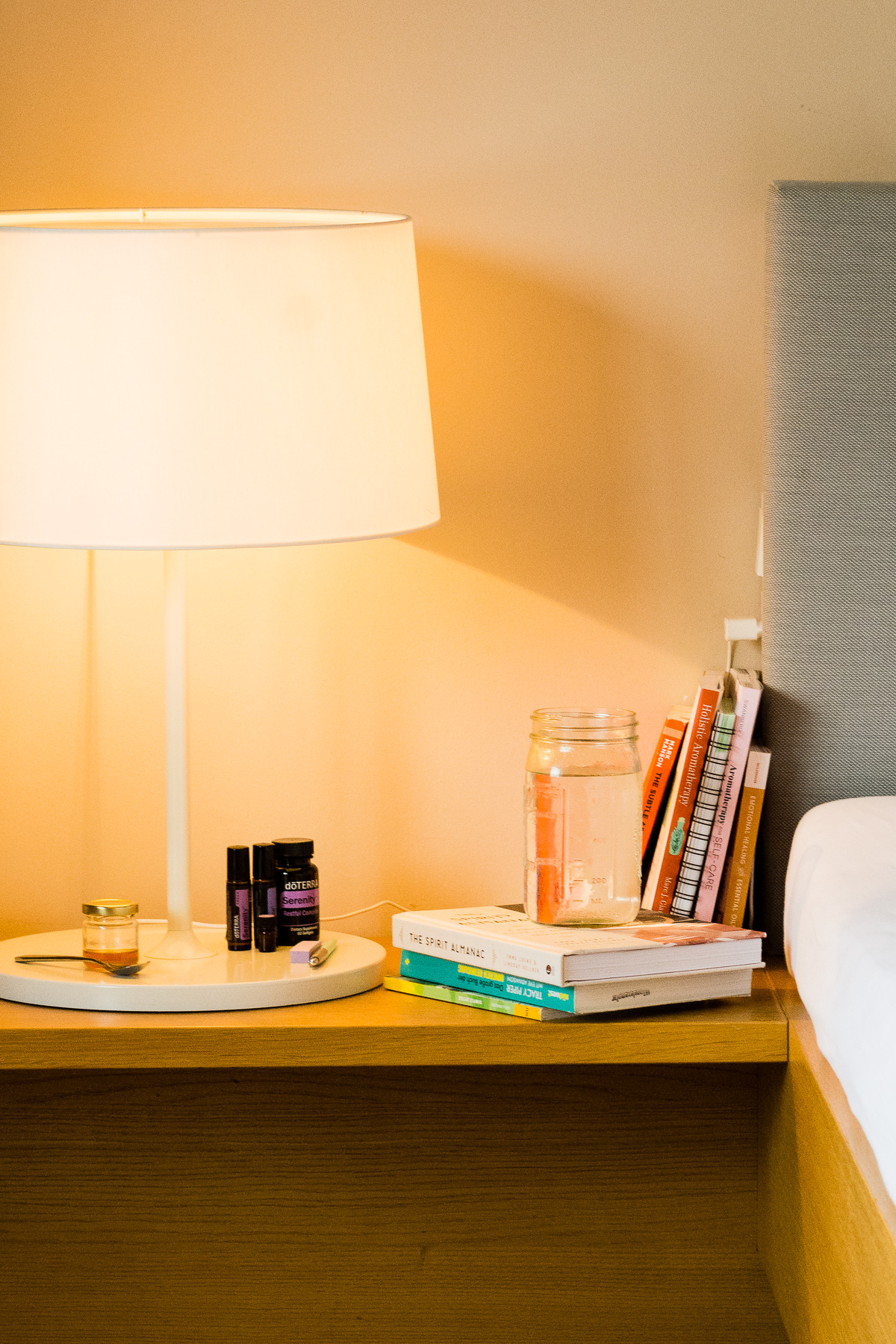 Tisch neben einem Bett mit einer Lampe, Büchern und einem Glas Wasser.