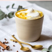 Keramikbecher mit Kurkuma Latte und Milchschaum.