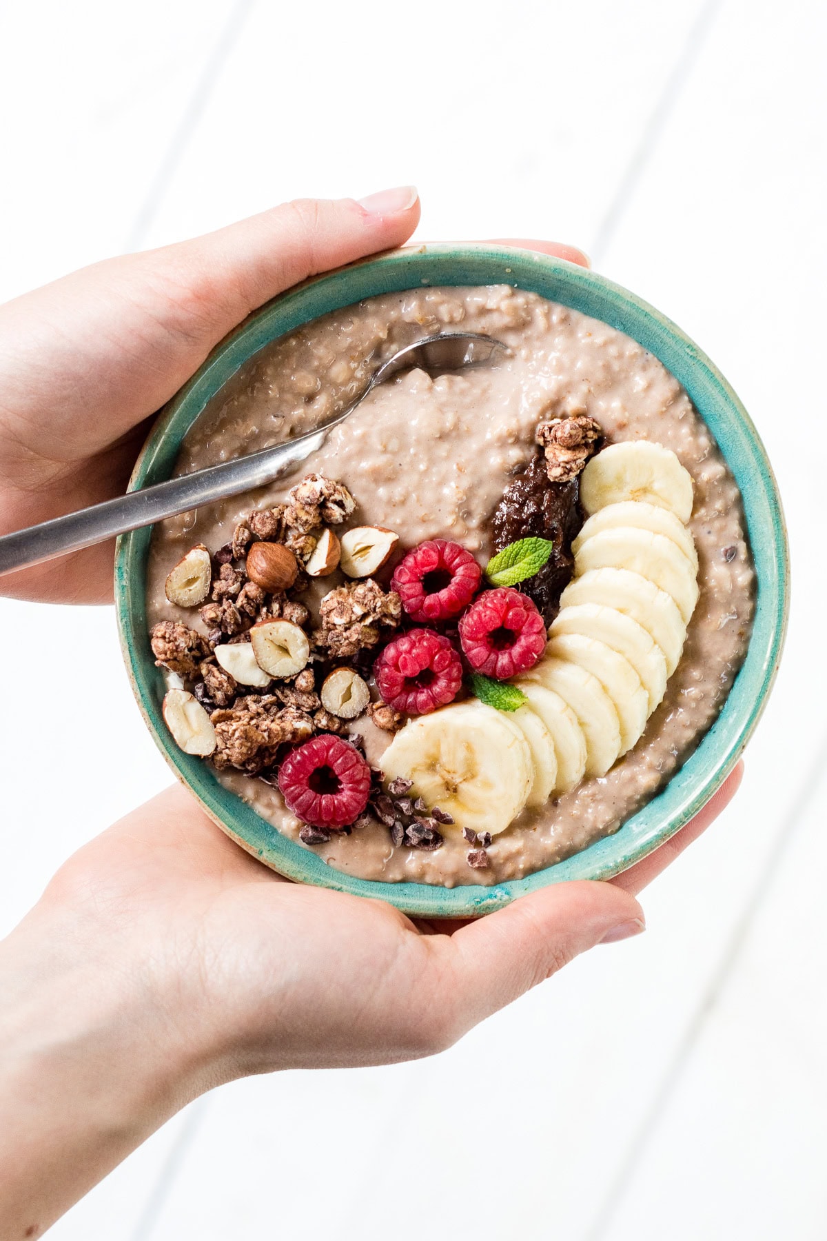 Topshot von einer Schüssel mit Porridge, Beeren, Bananen und Granola.