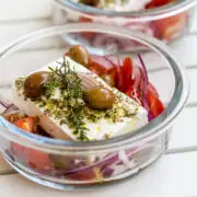 Glasschale gefüllt mit mariniertem Feta, Oliven, Zwiebeln und Tomaten.