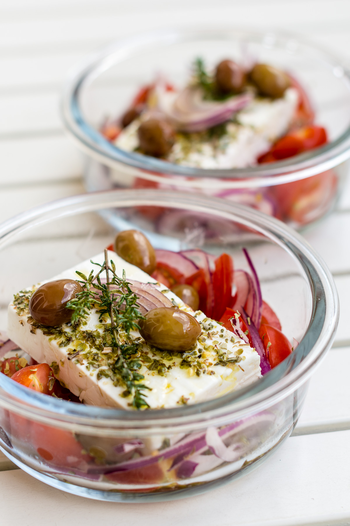 Glasschale gefüllt mit mariniertem Feta, Oliven, Zwiebeln und Tomaten.