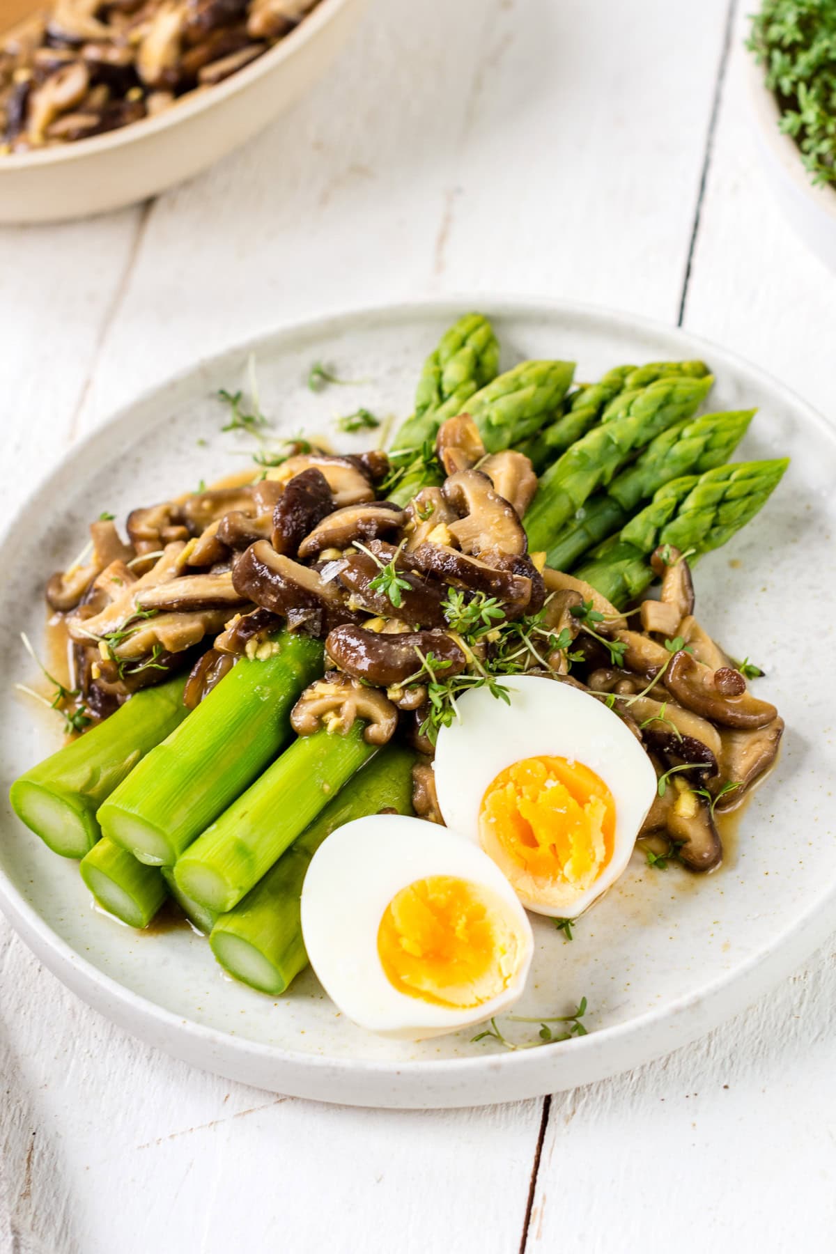 Pinne das Foto, um das Rezept für den Spargelsalat mit Shitake zu speichern! Teller mit Spargelsalat und Pilzen und gekochten Eiern auf einem weißem Teller.