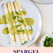 Zwei Teller mit weißem Spargel und einer grünen Sauce Hollandaise und Schnittlauch.
