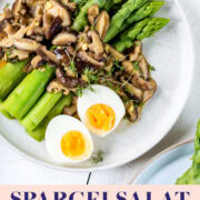 Teller mit Spargelsalat und Pilzen und gekochten Eiern auf einem weißem Teller.