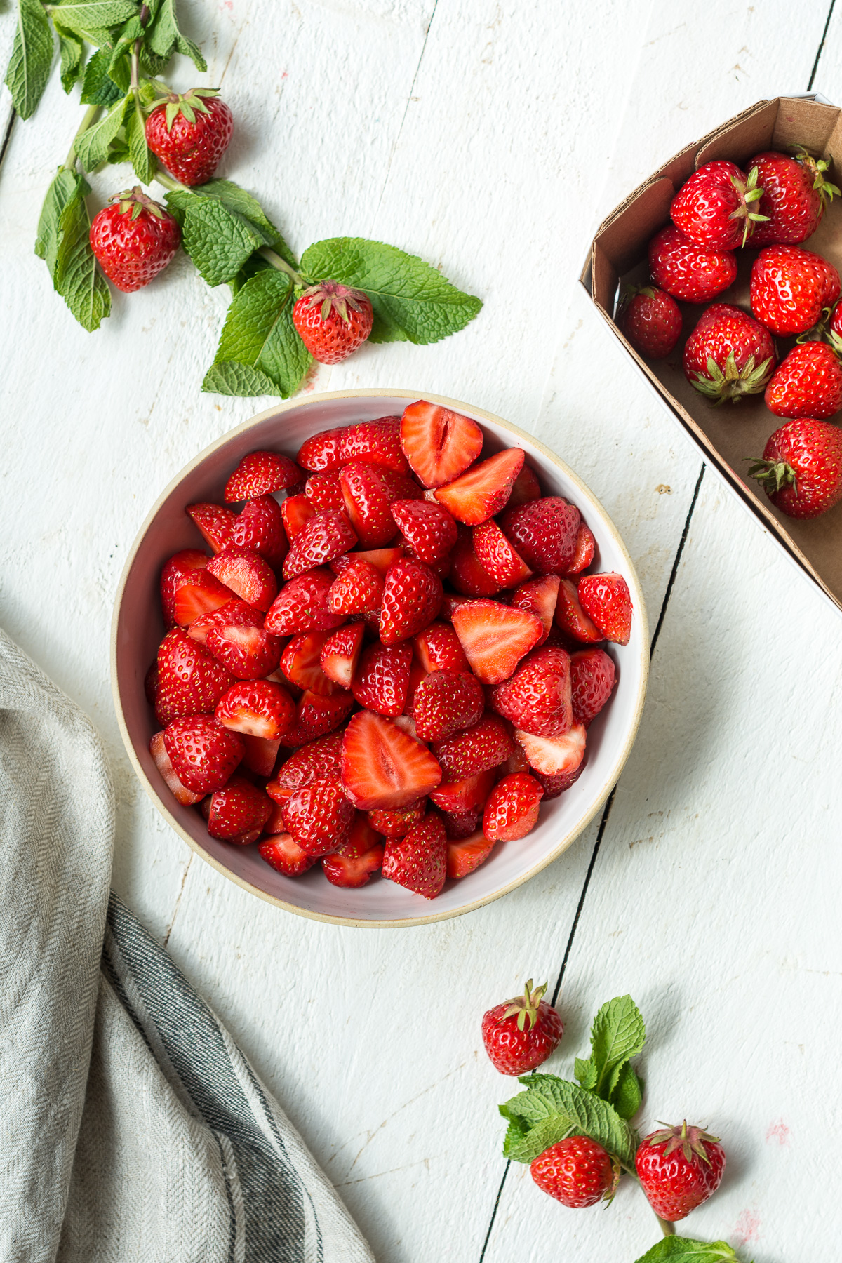 Topshot von Erdbeeren in weisser Schale und Minze