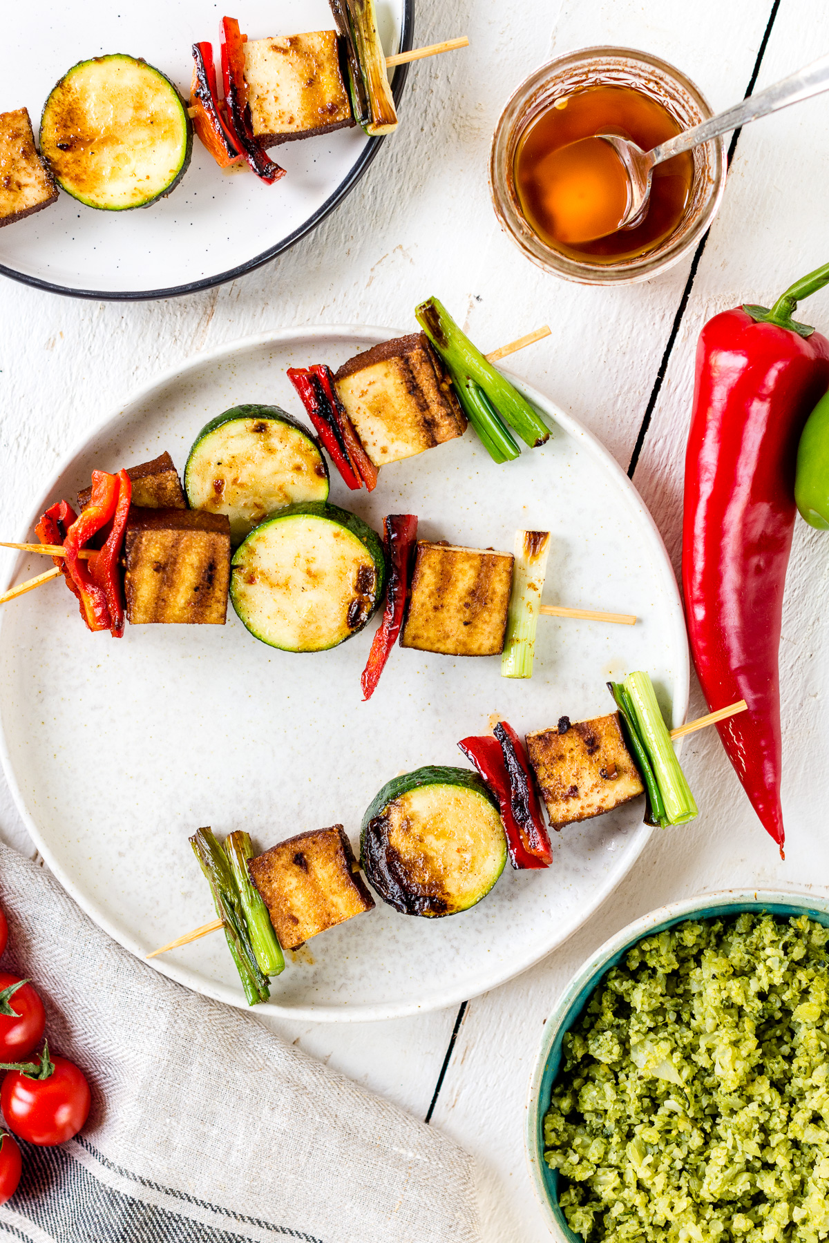 Topshot von zwei Tellern mit veganen Grillspießen mit Tofu und Gemüse.