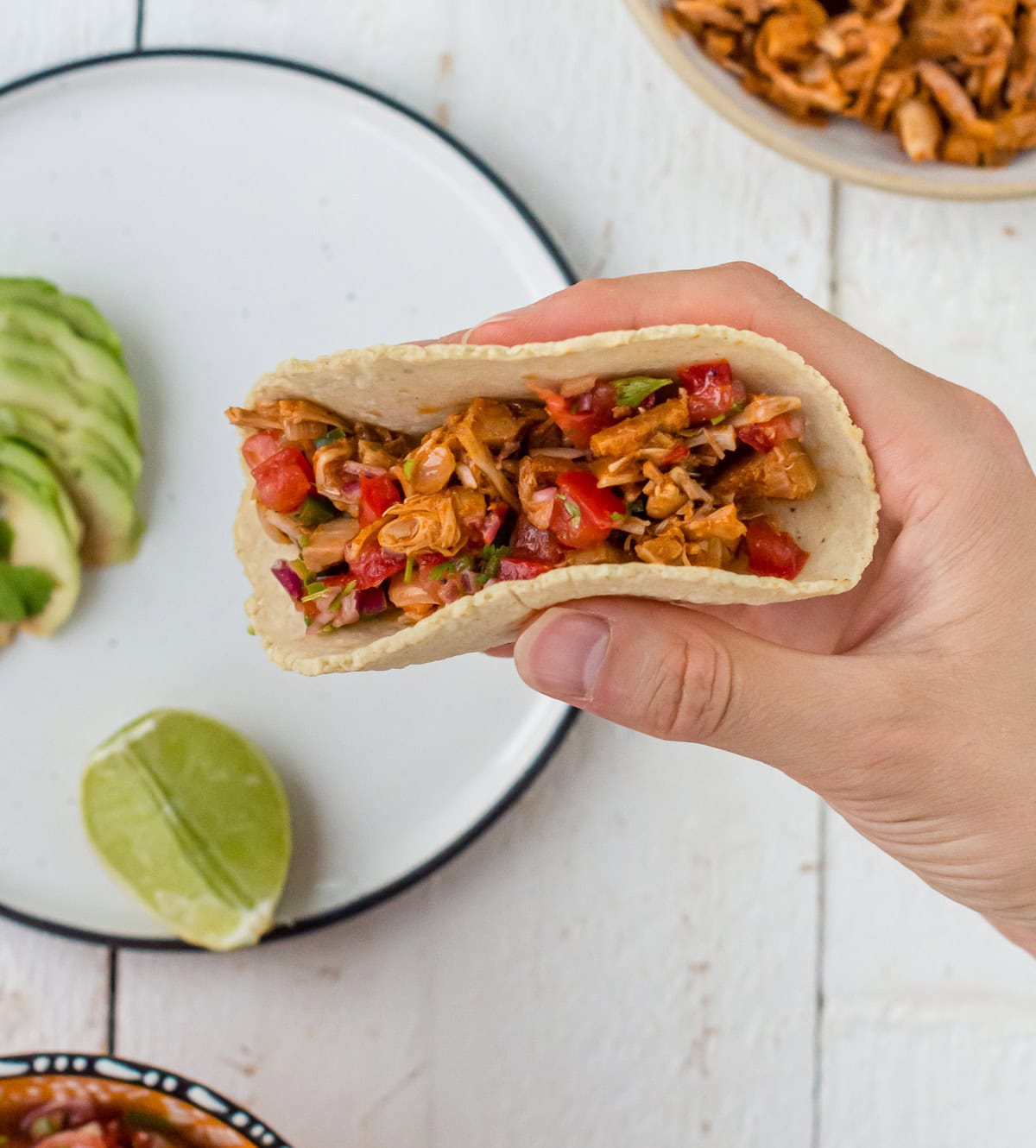 Jackfruit Taco mit frisch gebackenem Tortilla aus Maismehl in einer Hand