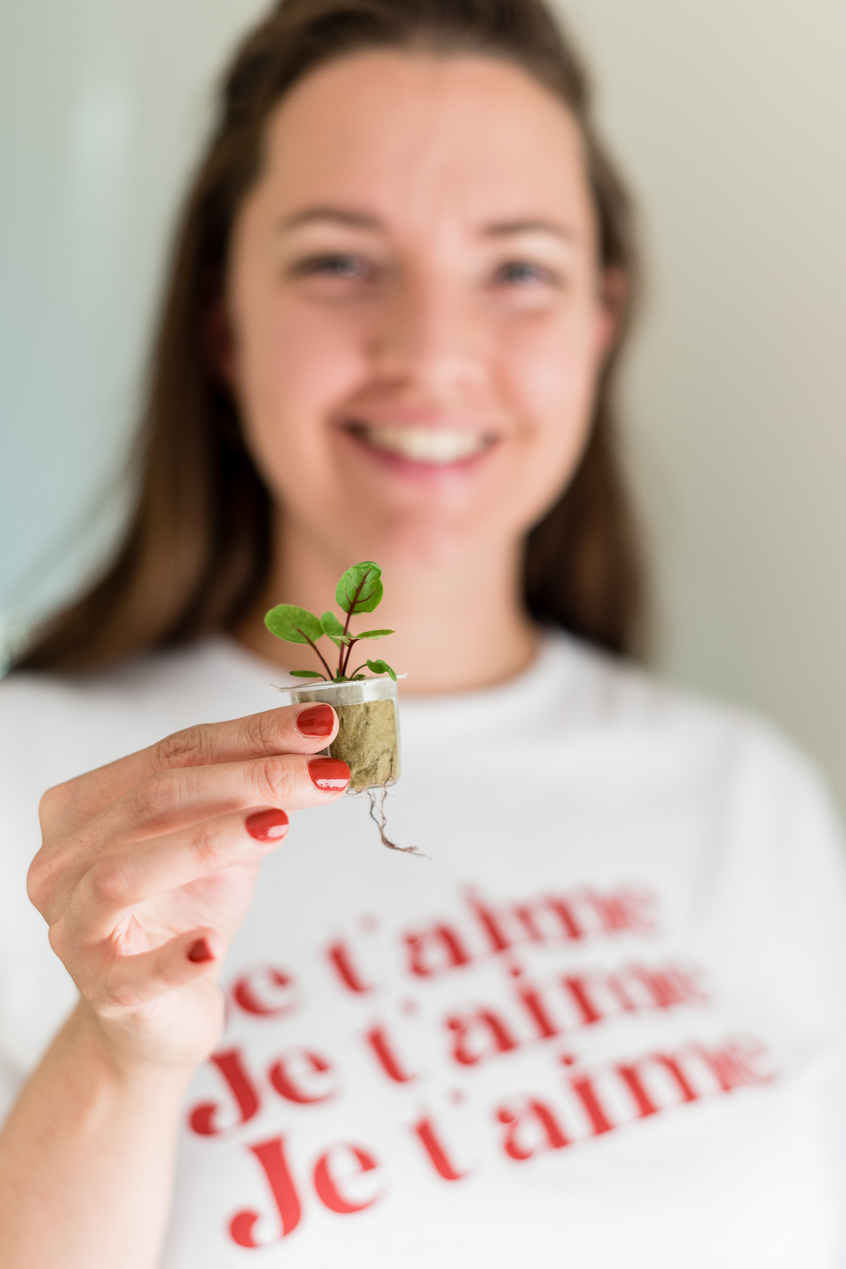 Lächelnde Frau mit kleiner Pflanze in der Hand
