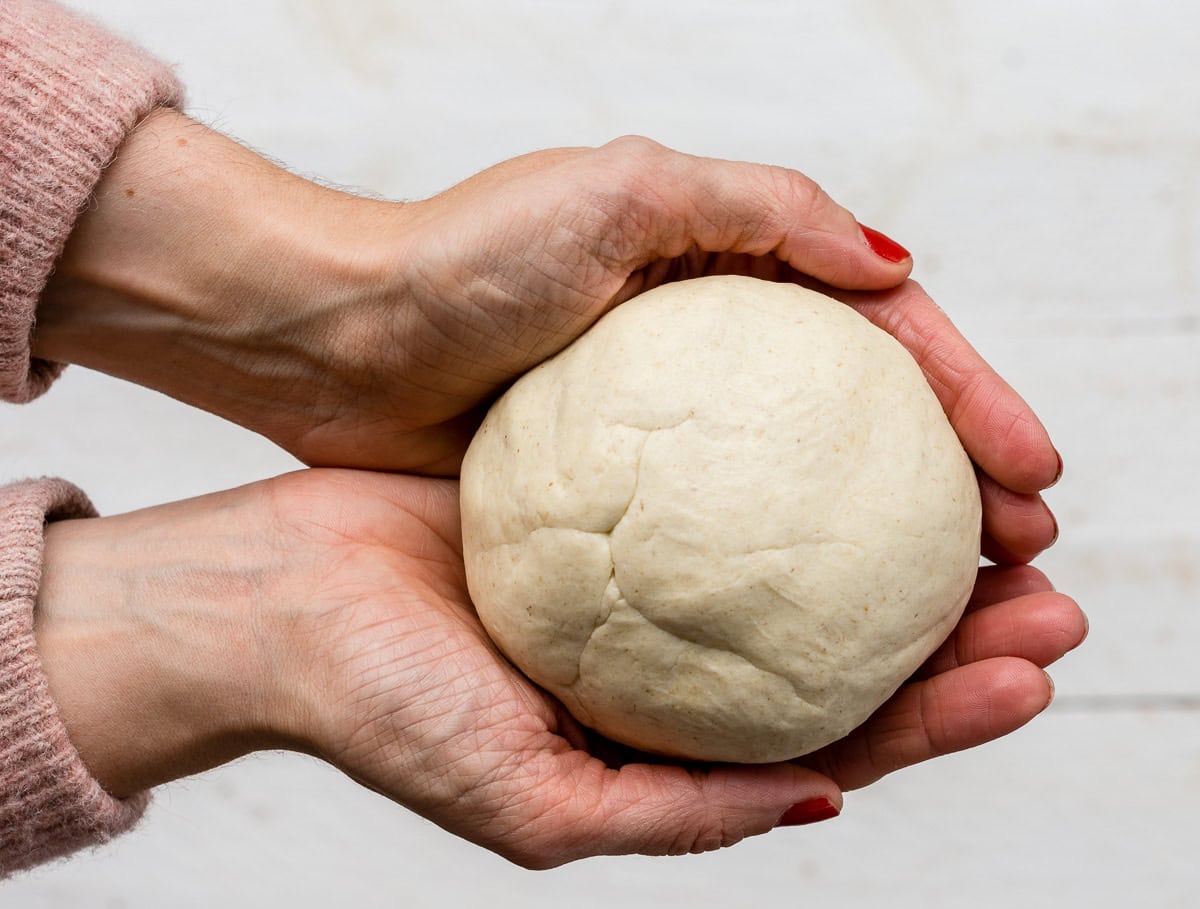 Hände mit Kuschelpulli halten eine Portion glutenfreien Flammkuchenteig