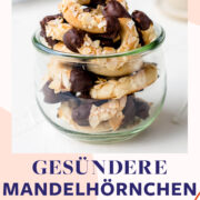 Mini-Mandelhörnchen in einem Glas mit Tee und Backblech im Hintergrund