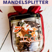 Weihnachtlich dekoriertes Glas gefüllt mit Mandelsplittern auf weißem Untergrund.