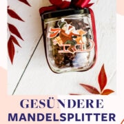 Weihnachtlich dekoriertes Glas gefüllt mit Mandelsplittern auf weißem Untergrund.