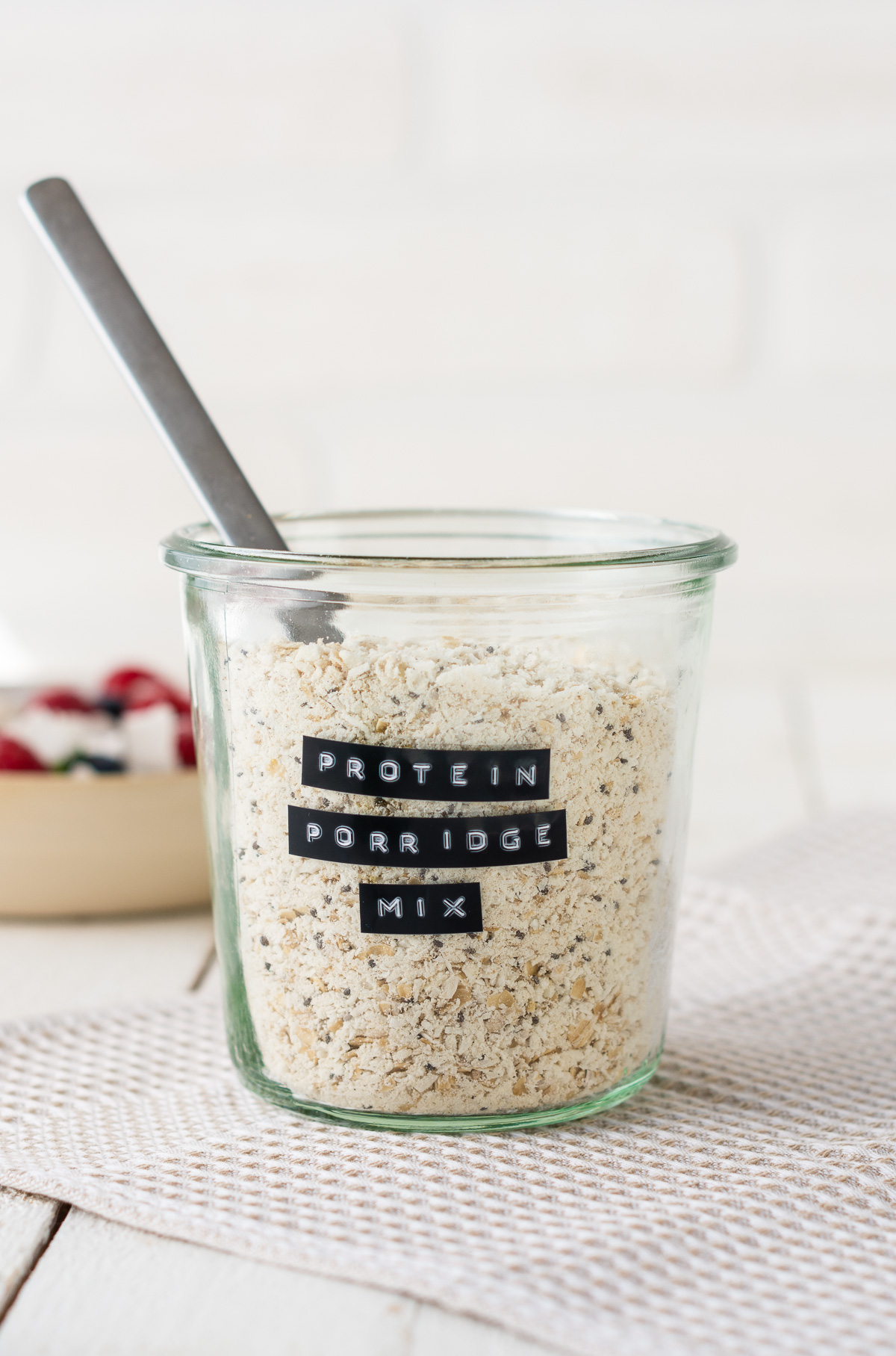 Foto von einem Glas Protein Porridge Mix vor weißem Hintergrund.