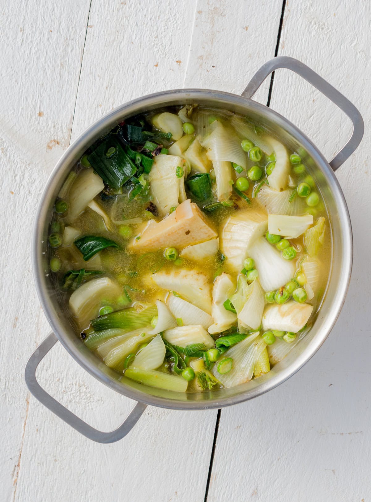 Topshot von einem Topf Gemüsesuppe auf weißem Untergrund.