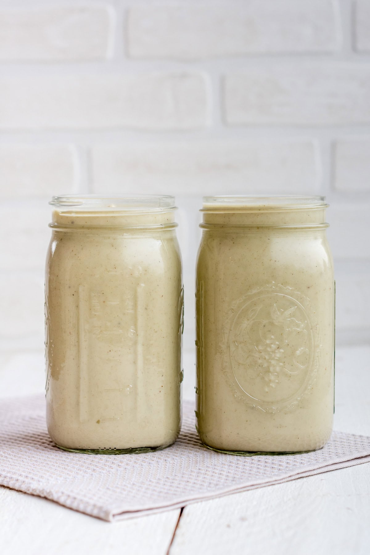 Zwei Gläser mit fertig gekochter Topinambursuppe vor weißem Hintergrund.