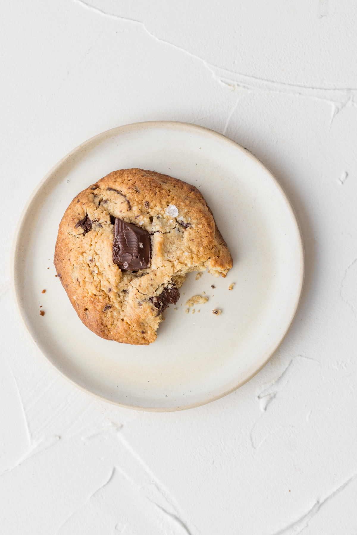 Topshot von einem Chocolate Chip Cookie mit Meersalz auf einem weißen Teller.