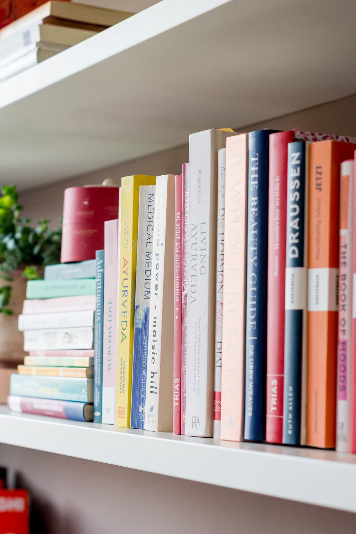 Foto von einem ästhetischen Bücherregal in dem verschiedene Bücher rund um das Thema Wellbeing stehen.